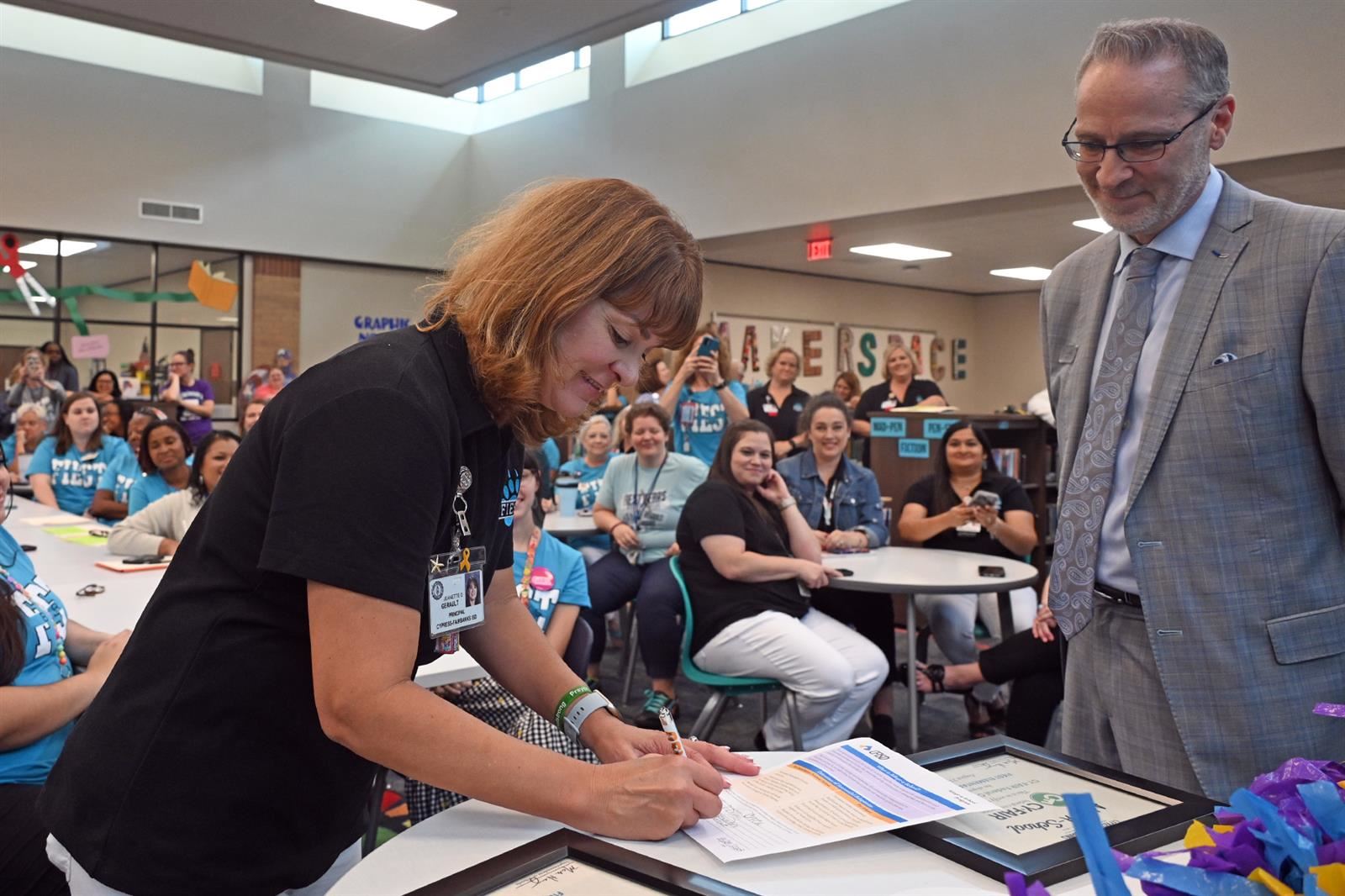 Dr. Jeanette Gerault, Fiest principal, left, signs an Adopt-a-School partnership agreement.